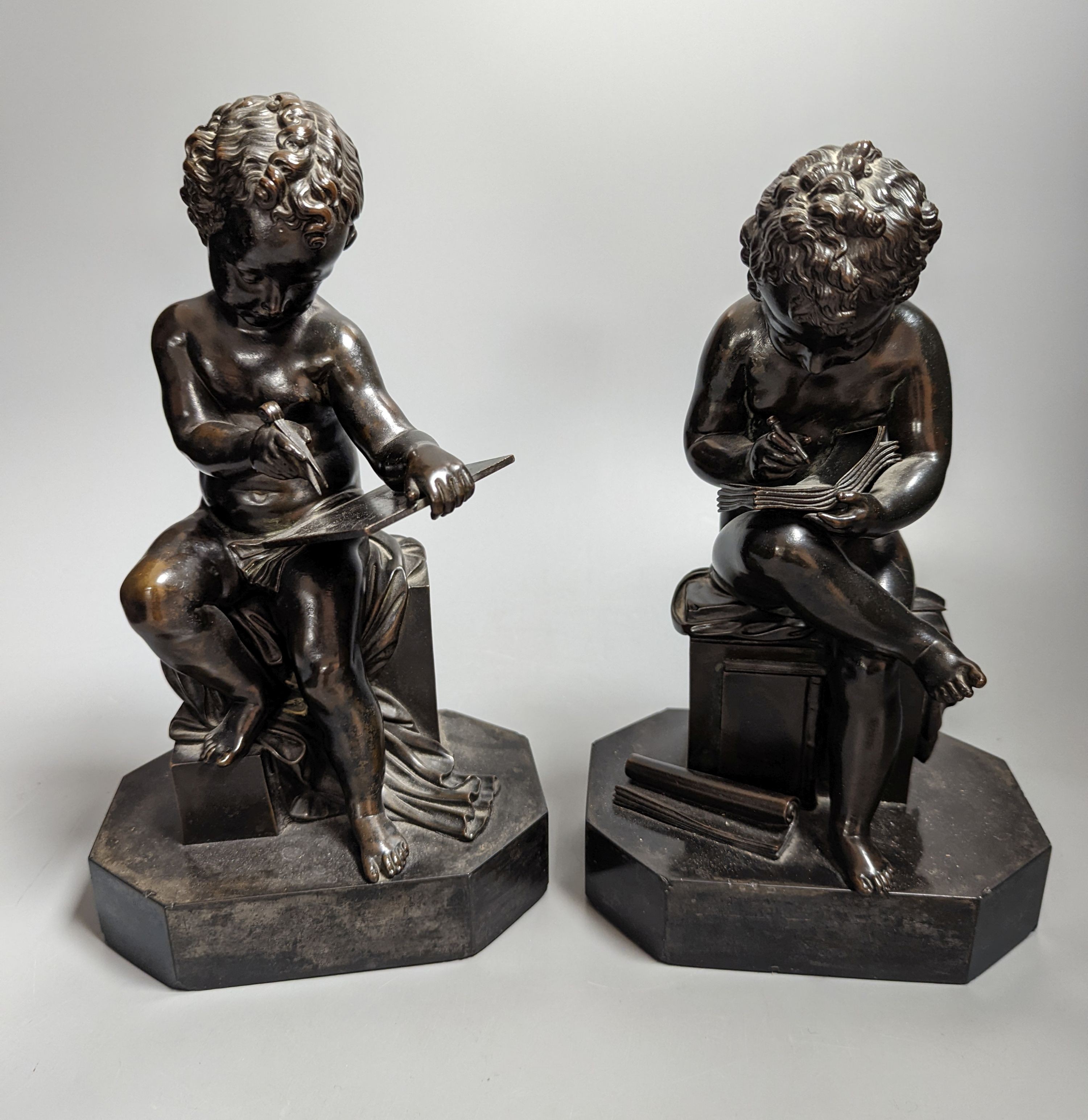 A pair of late 19th century bronze figures of seated putti plotting and writing notes, 26cm